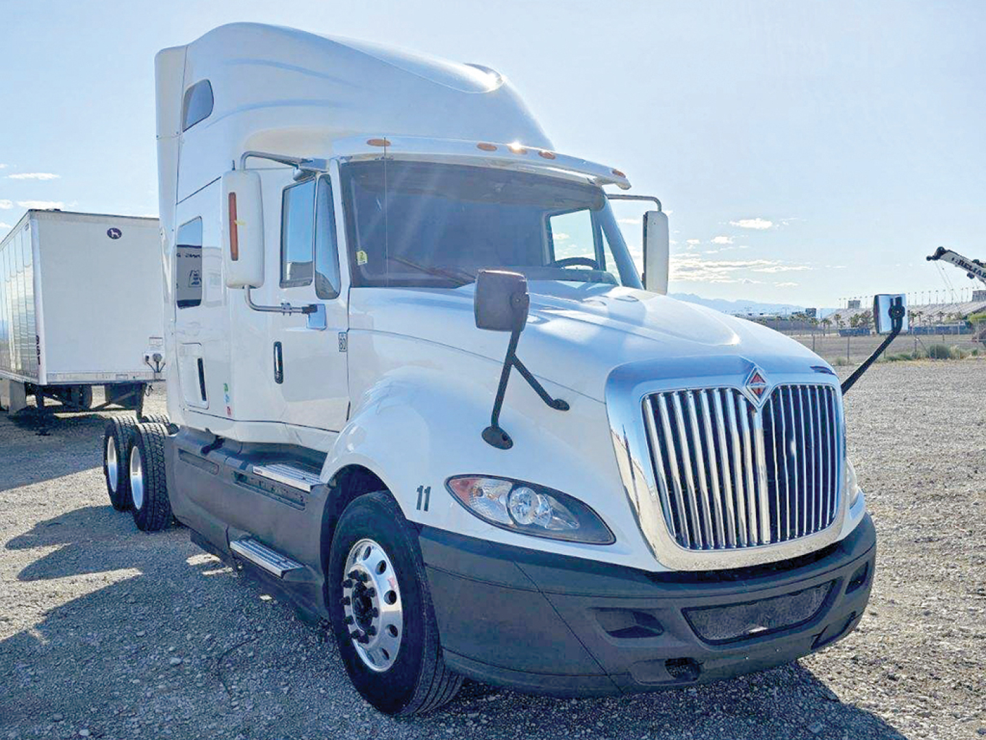 Truck cab with attached sleeper, International LT625 model, white with chrome grille and dual rear axles visible, side mirror views, dealership lot.