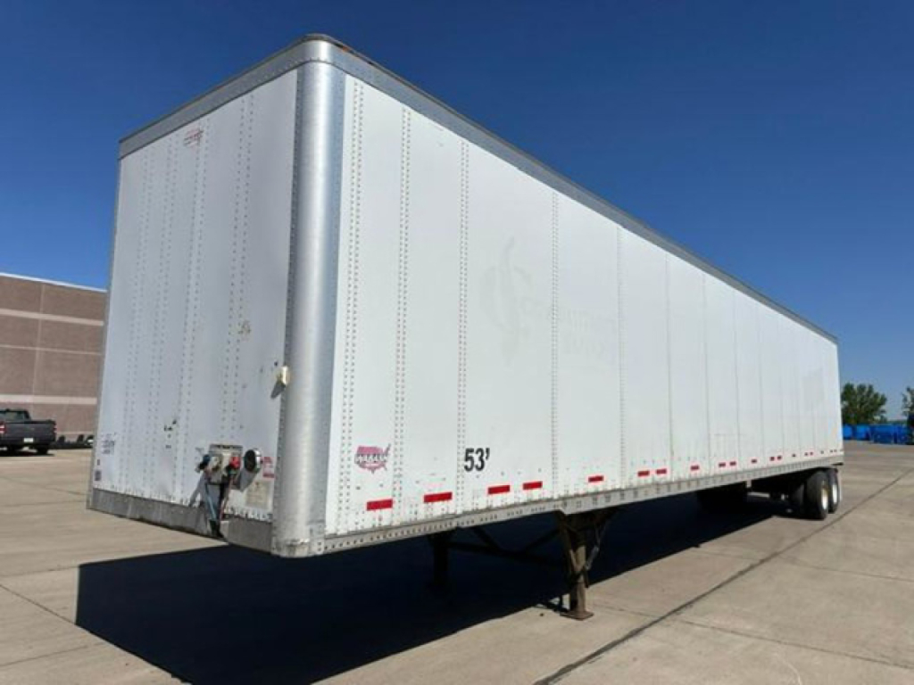 Trailer side view showing a white 53' box with dual rear wheels and landing gear, exterior riveted panels, and reflective striping.