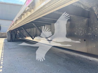 Trailer underside and deck edge of a Transcraft D-Eagle II drop deck trailer showing the side rail and structural beams.