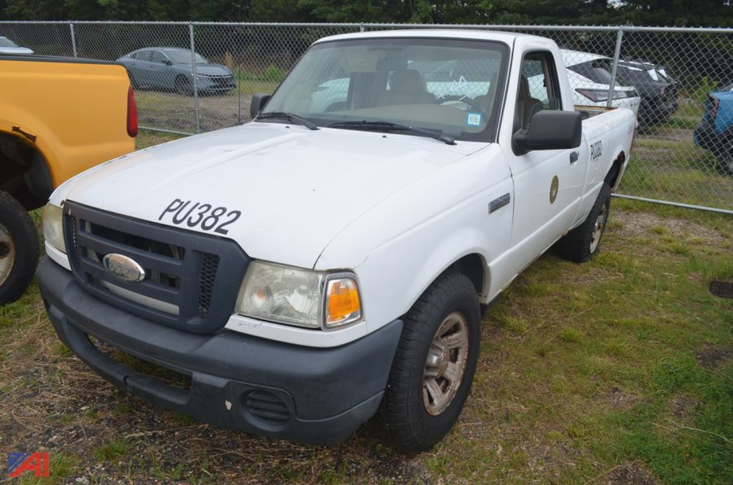 White 2008 Ford Ranger pickup truck with a black front bumper and grille, number 'PU382' written on the hood, 4x4 badge on the side, and a utility-style cab; a chain-link fence and other vehicles in the background.