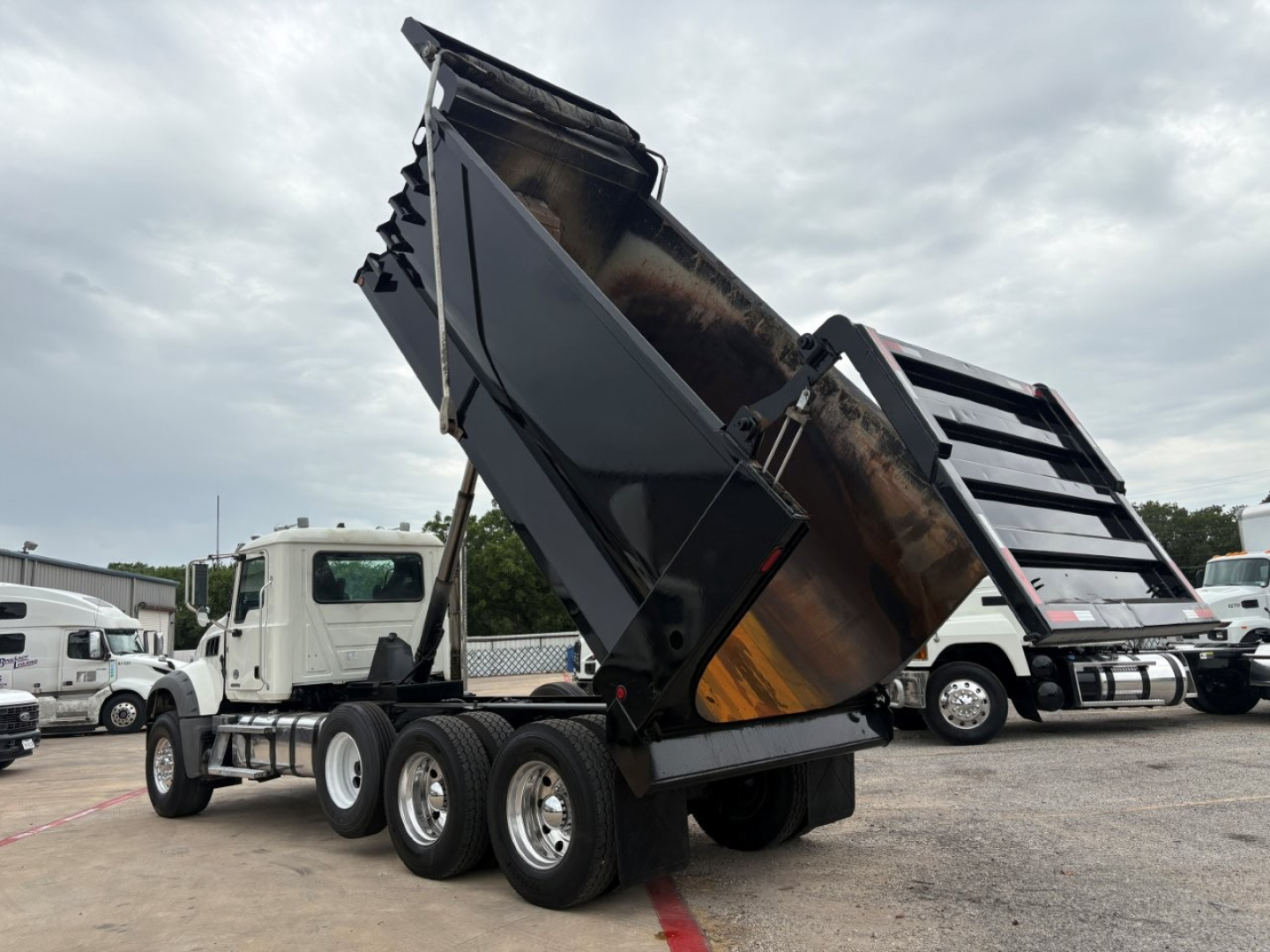 Dump truck with raised dump bed showing Mack GR64F chassis and dual rear axles.
