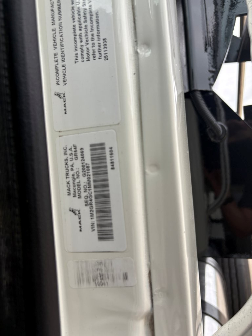 Label stickers on door jamb of a 2021 Mack GR64F dump truck showing VIN and serial/barcode text.