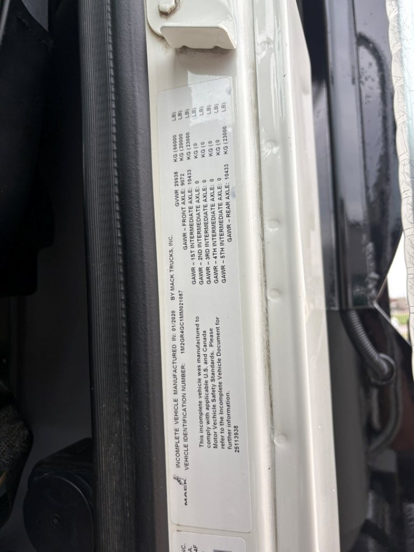 Label on door jamb with vehicle VIN and specifications text for a Mack GR64F dump truck. Visible: long block of small text, numbers arranged in a table, likely VIN and production details.