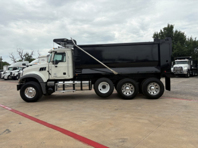 Dump truck side view showing 2021 Mack GR64F with black dump bed and white cab.