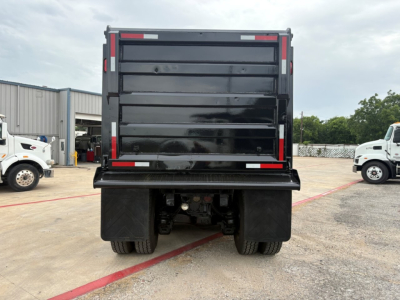 Dump truck bed rear view showing Mack GR64F with black dump bed, taillights, and rear wheels visible.