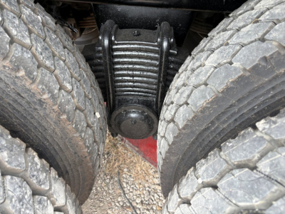Rear view of heavy-duty axle housing between dual rear tires showing differential and suspension components.
