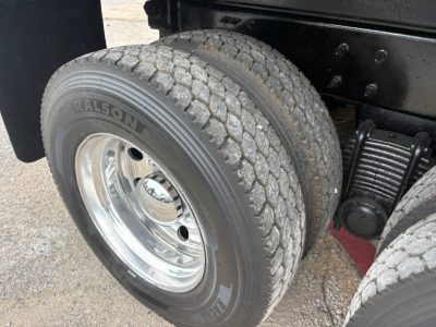 Two rear wheels of a Mack GR64F dump truck showing Falken tire branding on the sidewalls, chrome wheel rims, and part of the suspension/components.