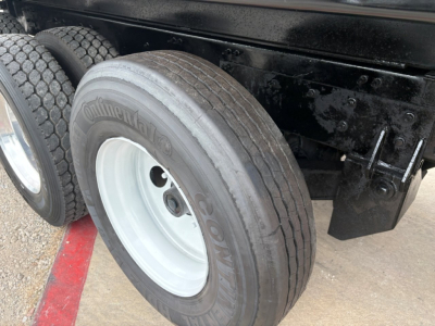 Truck wheel and dual rear tires of a Mack GR64F chassis showing Continental tire and white steel rim with black undercarriage and splash guard.