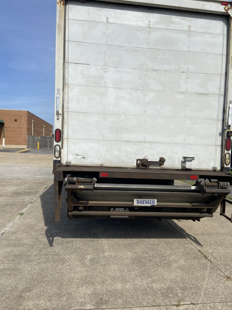 Truck rear view showing cargo box and hydraulic lift gate with license plate area and back doors.