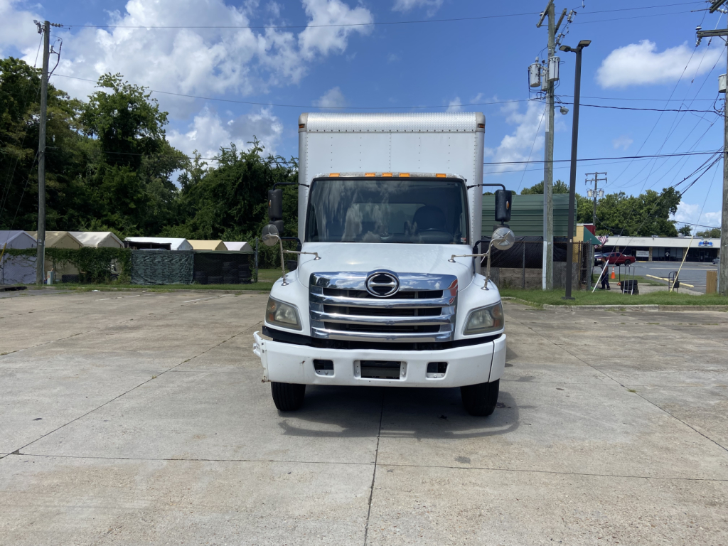Front view of a white 2016 Hino conventional truck in a parking lot, with a box cargo area and grille details visible.