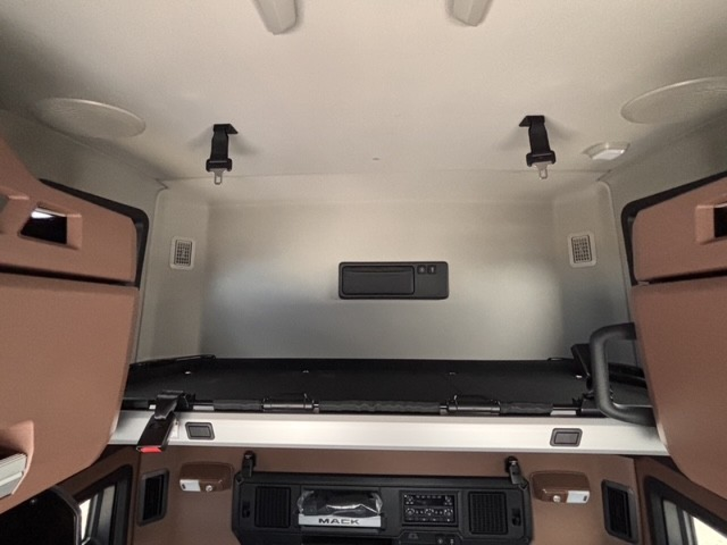 Mack PR64T76H tractor cab interior showing sleeper area and overhead bunk storage units with brown cabinetry and cargo tray.