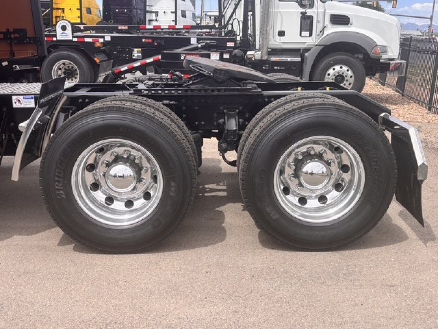 Dual rear axle on a new Mack PR64T76H truck chassis showing chrome wheels and tires with fenders, part of a semi-truck trailer setup.