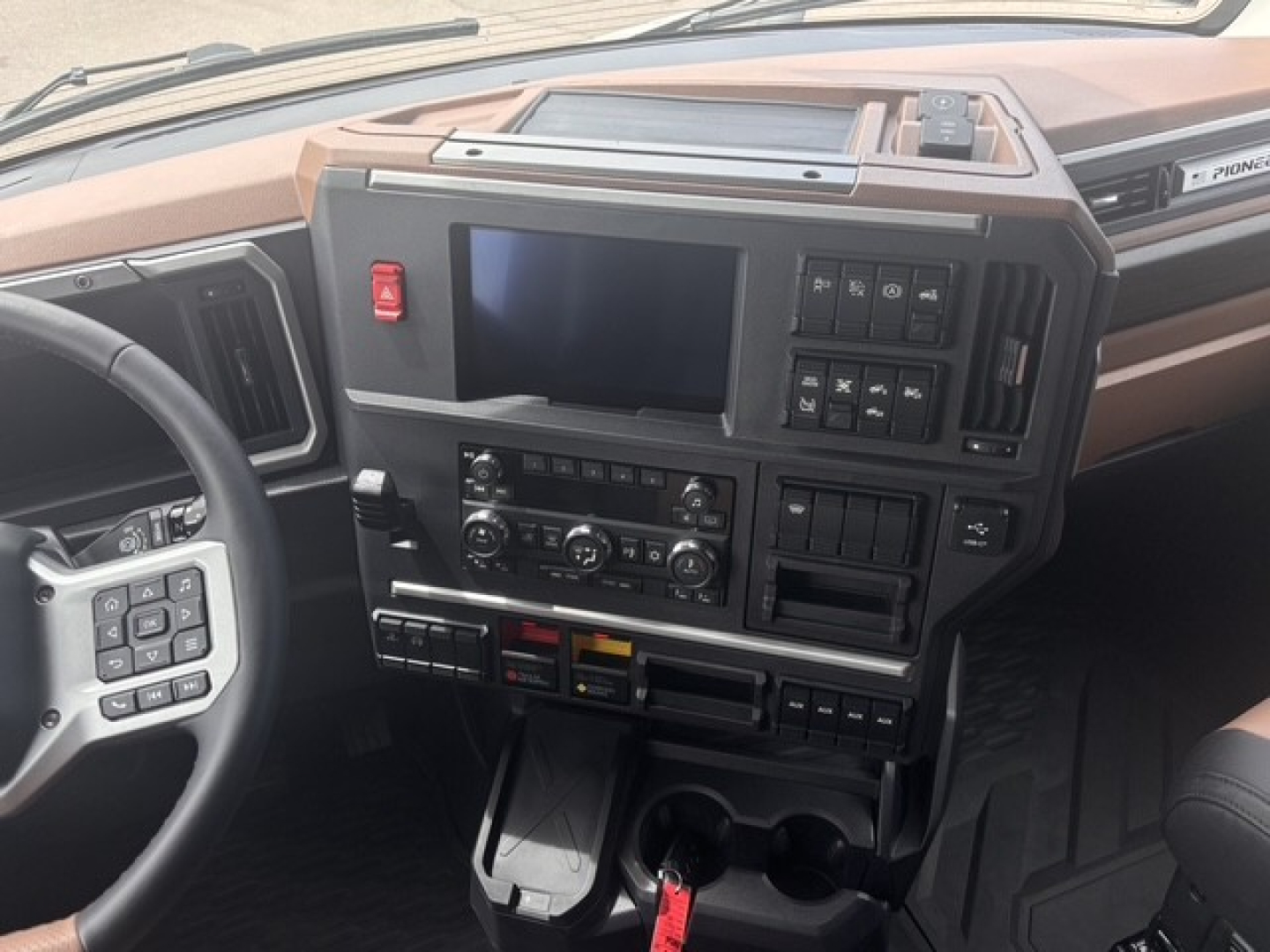 Interior dash of a Mack PR64T76H truck showing steering wheel, digital display, control panels, and center console.