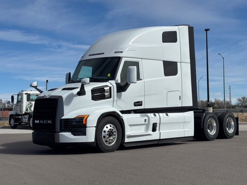 Mack PR64T76H conventional sleeper tractor in white, front-left view, weighing highway truck with sleeper cab and dual rear axles.