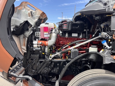 Mack PR64T76H engine bay showing red engine, various hoses, wiring, and air intake components.