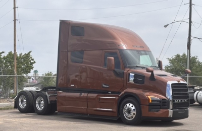 Mack PR64T76H tractor-trailer cab in brown showing aerodynamic sleeper with badge and chrome grille