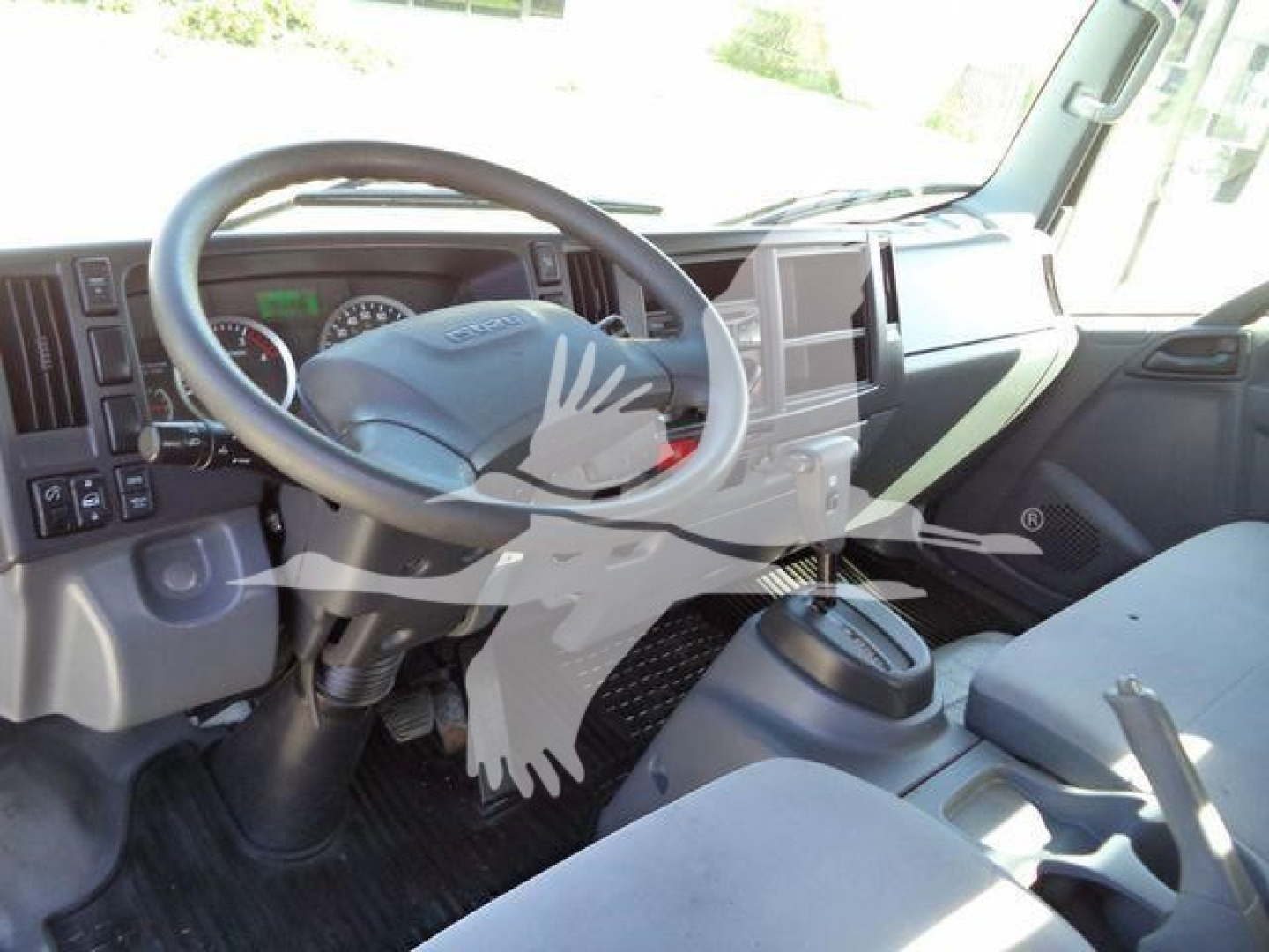 Isuzu NPR XD truck interior showing steering wheel and dashboard, with front seats and center console.