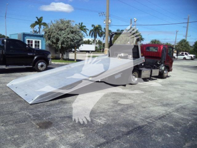 Isuzu NPR XD rollback tow truck with a lowered aluminum ramp on a sunny day.