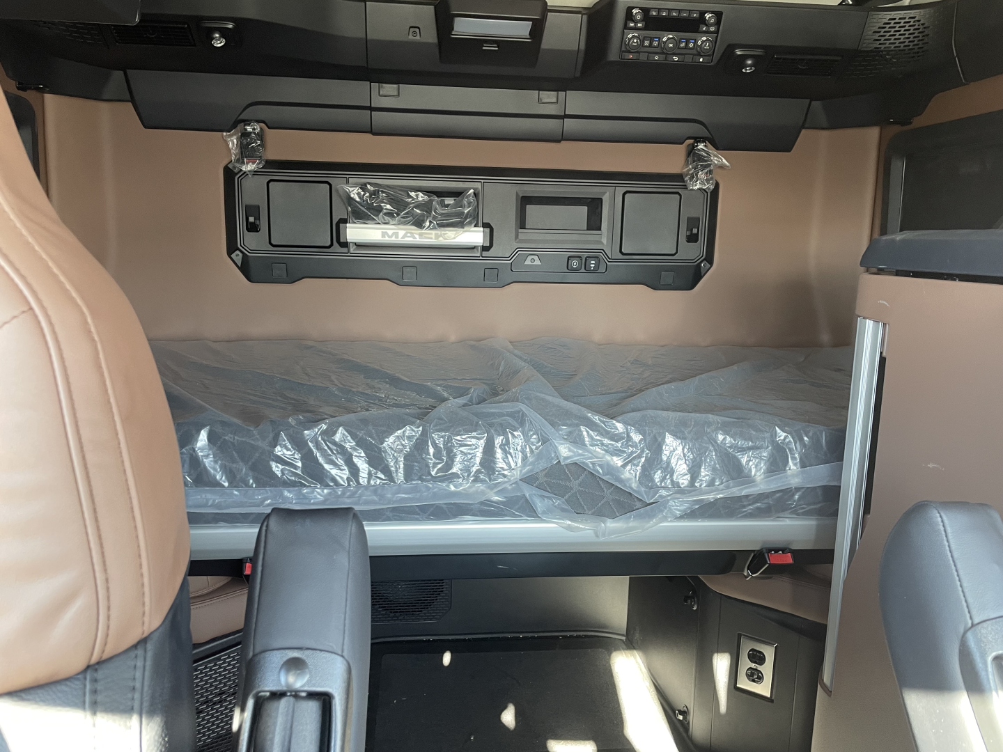 Cab interior of a Mack PR64T76H showing sleeper bunk area and dash with storage compartments.