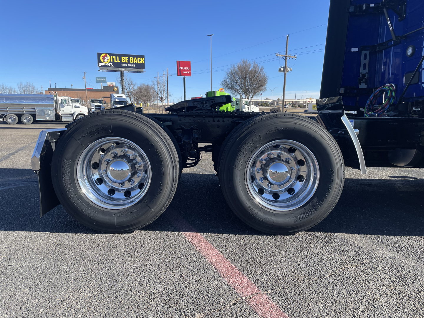 Dual rear drive wheels on a Mack PR64T76H heavy truck chassis showing chrome hubcaps and black tires; side of frame and components visible.