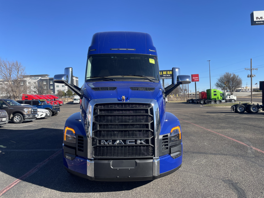 Front view of a blue Mack PR64T76H truck in a dealership lot showing the grille with MACK badge and headlight assemblies.