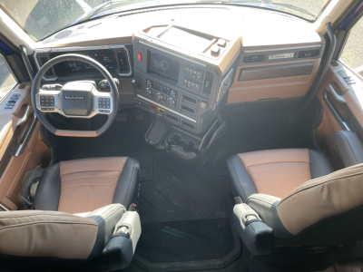 Interior of a Mack PR64T76H cab showing steering wheel, dashboard with controls, tan and black seats.