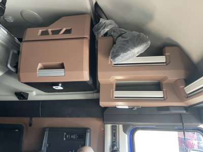 Truck cab interior with brown overhead storage compartments and mounted controls visible.