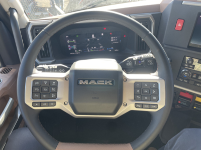 Steering wheel of a Mack PR64T76H truck showing mounted controls and digital dash display in the cockpit.