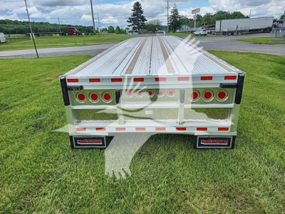 Flatbed trailer rear view showing aluminum deck with side rails and multiple round taillight cutouts.