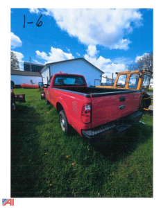 Red 2011 Ford F-250 Super Duty pickup truck with plow attachment in a grassy lot, rear view showing tailgate and bed.