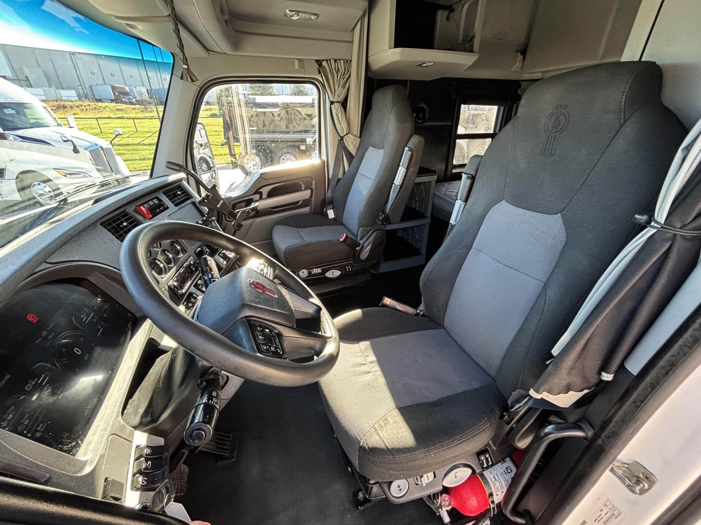 Kenworth T680 truck cab interior with driver and passenger seats, steering wheel, and dashboard visible.