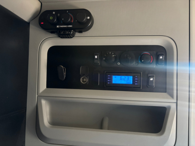 Kenworth T680 cab interior dash area showing HVAC controls and an after market blue digital display panel.