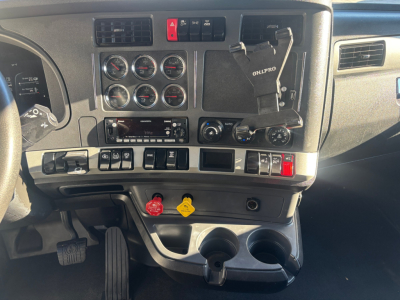 Kenworth T680 dashboard interior showing gauges, switches, cup holders, and red/yellow warning knobs.