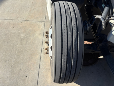 Dual-steelband Kenworth T680 front steer tires and wheel assembly showing axle and suspension components.