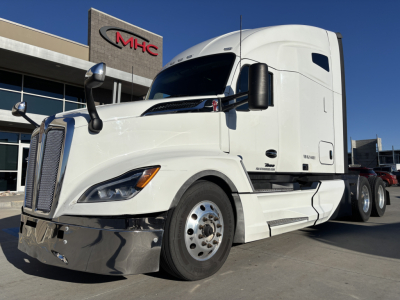 Kenworth T680 conventional sleeper truck showing front grille and white cab with chrome bumper and dual rear axles.