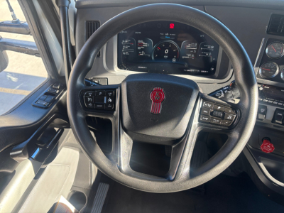 Kenworth T680 cockpit showing steering wheel and dashboard with instrument cluster and control stalks