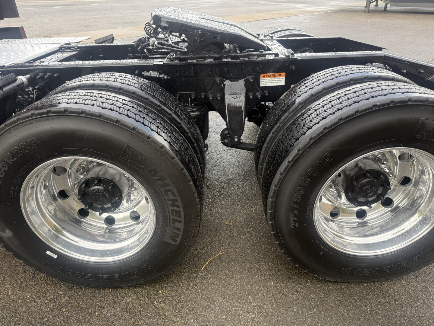 Dual rear axles with chrome wheels and Michelin tires; chassis frame and fifth-wheel area visible; no cargo pictured.