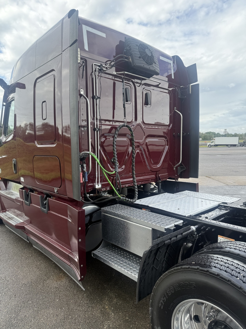 Freightliner Cascadia126 truck cab rear window area with exposed electrical wires and access panels; side steps and wheel visible.