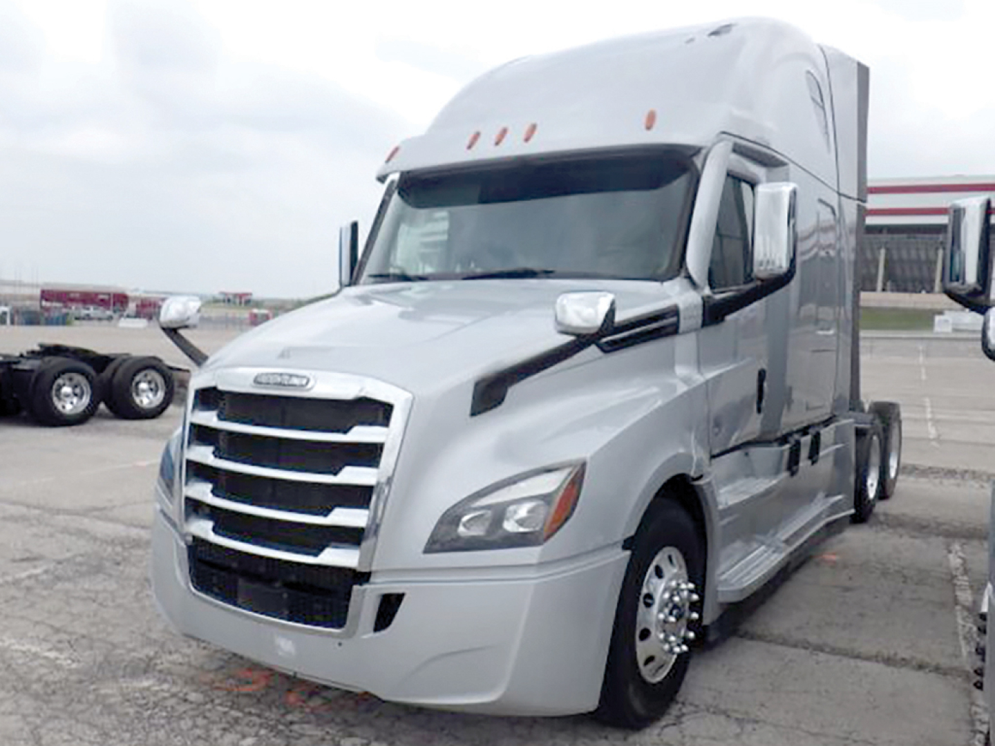 Truck cab showing a 2022 Freightliner Cascadia 126 sleeper with chrome grille and side mirrors, silver paint, daytime running lights, and front wheels.