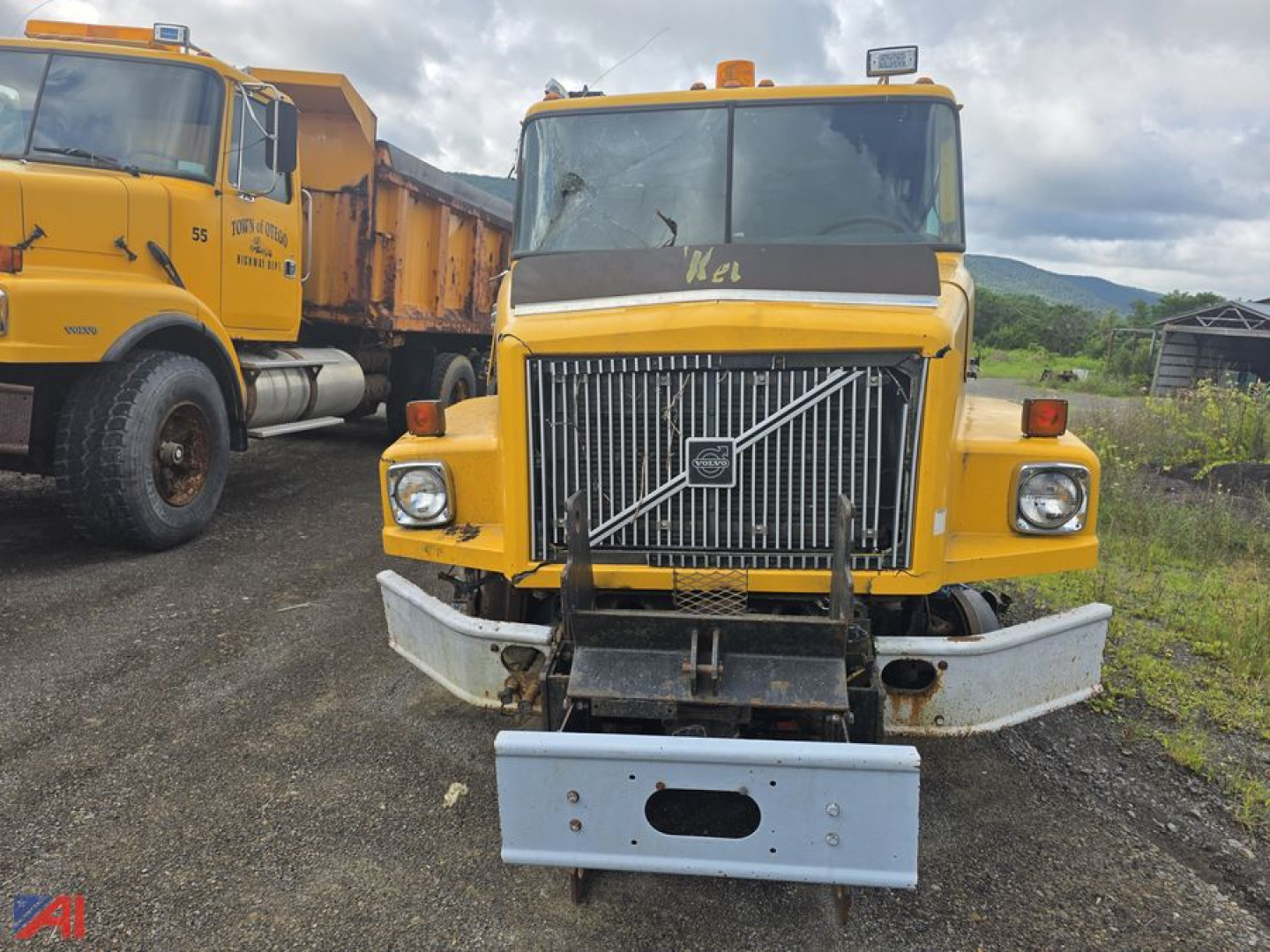 Volvo WG cab and chassis truck front view showing large grille, bumper, and salvage plate. Yellow paint with utility lights on roof.