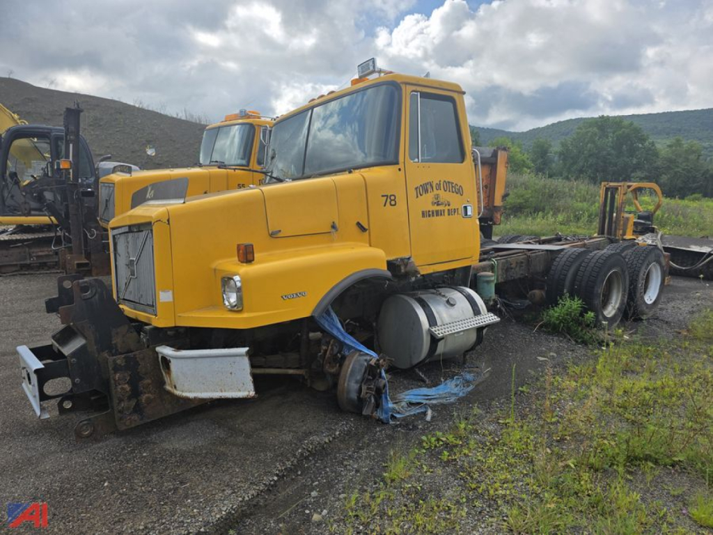 1996 Volvo WG cab and chassis truck with salvage/parts condition in an outdoor yard. Yellow cab, exposed wheels and chassis, missing front bumper and parts, with truck number 78 on door.