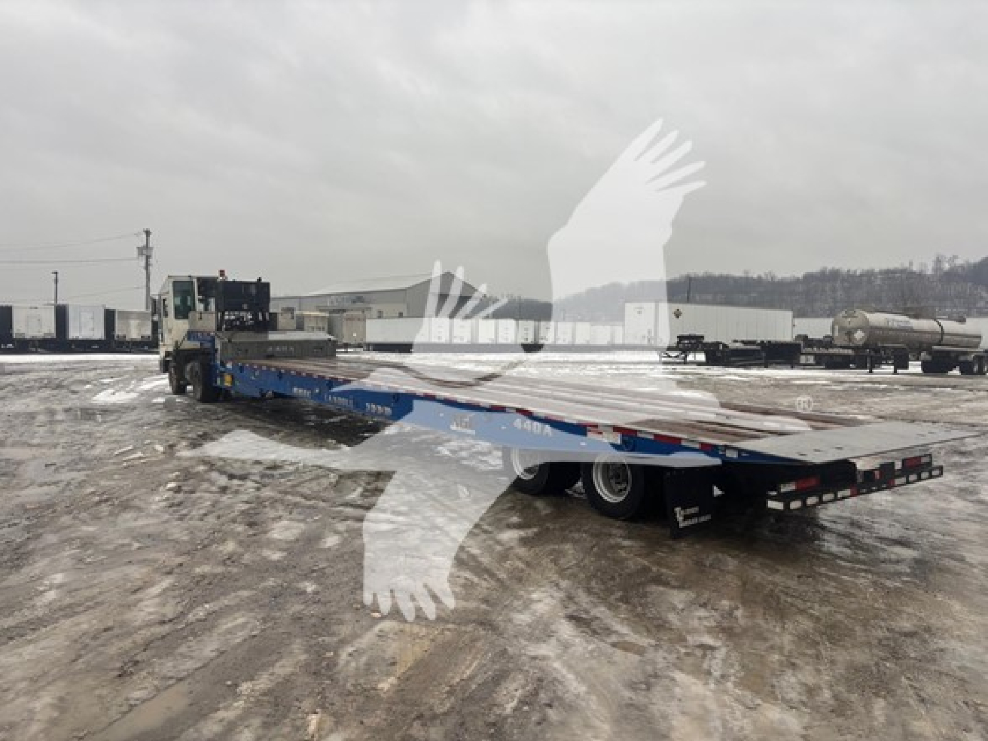 Landoll 2016 440B trailer in yard showing flatbed with dual rear axles and towing tractor in distance, VIN 1LH440WHXG1A22614