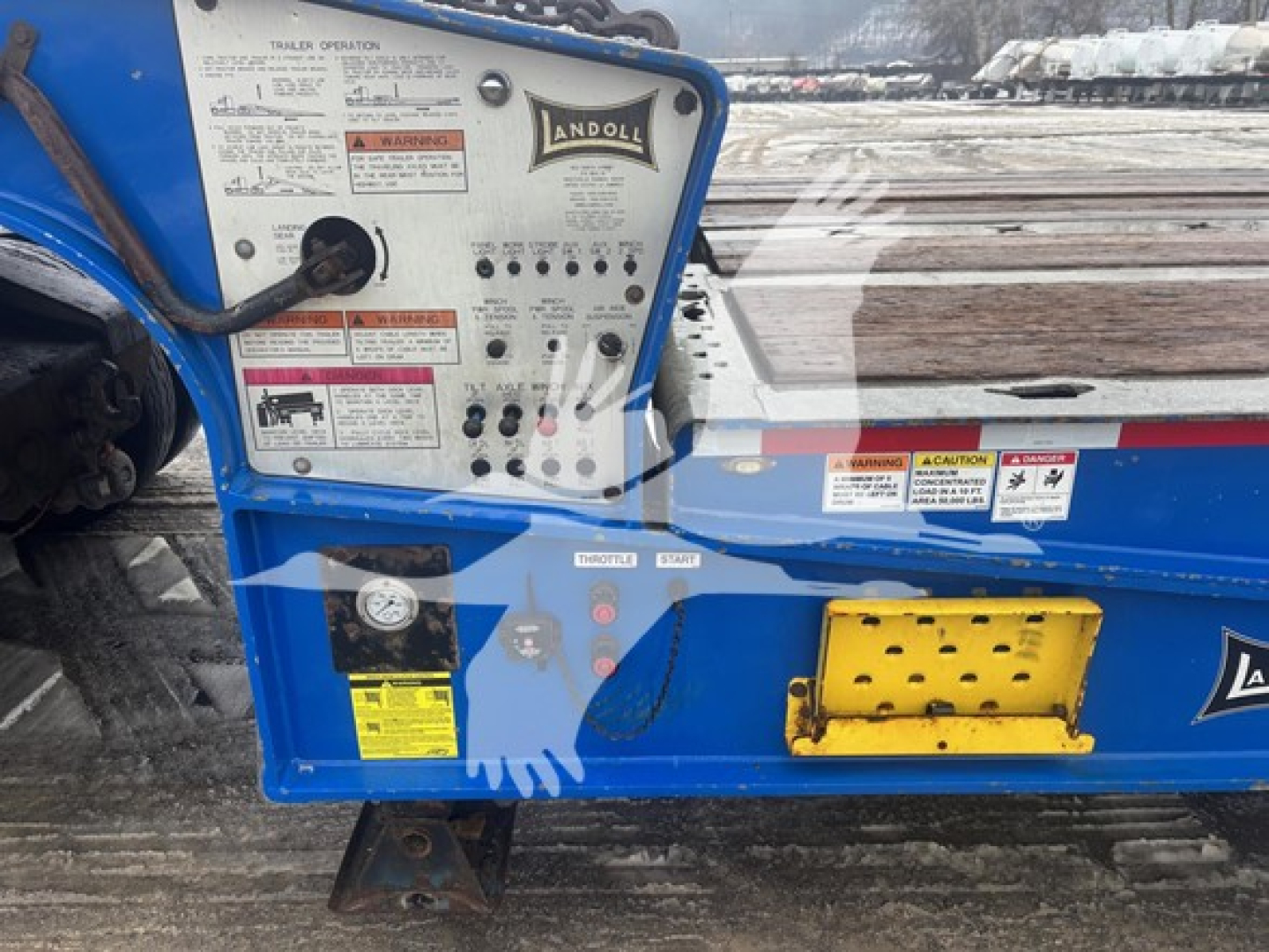 Landoll 440B trailer control panel with labels and stickers, blue body, wooden deck, yellow step, VIN plate area visible.
