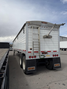 Timpte Super Hopper trailer rear view showing aluminum sides, tailgate, mud flaps with Timpte branding, and rear bumper lights.