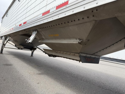 Trailer undercarriage showing bottom of a Timpte hopper trailer with a side apron and landing gear visible.