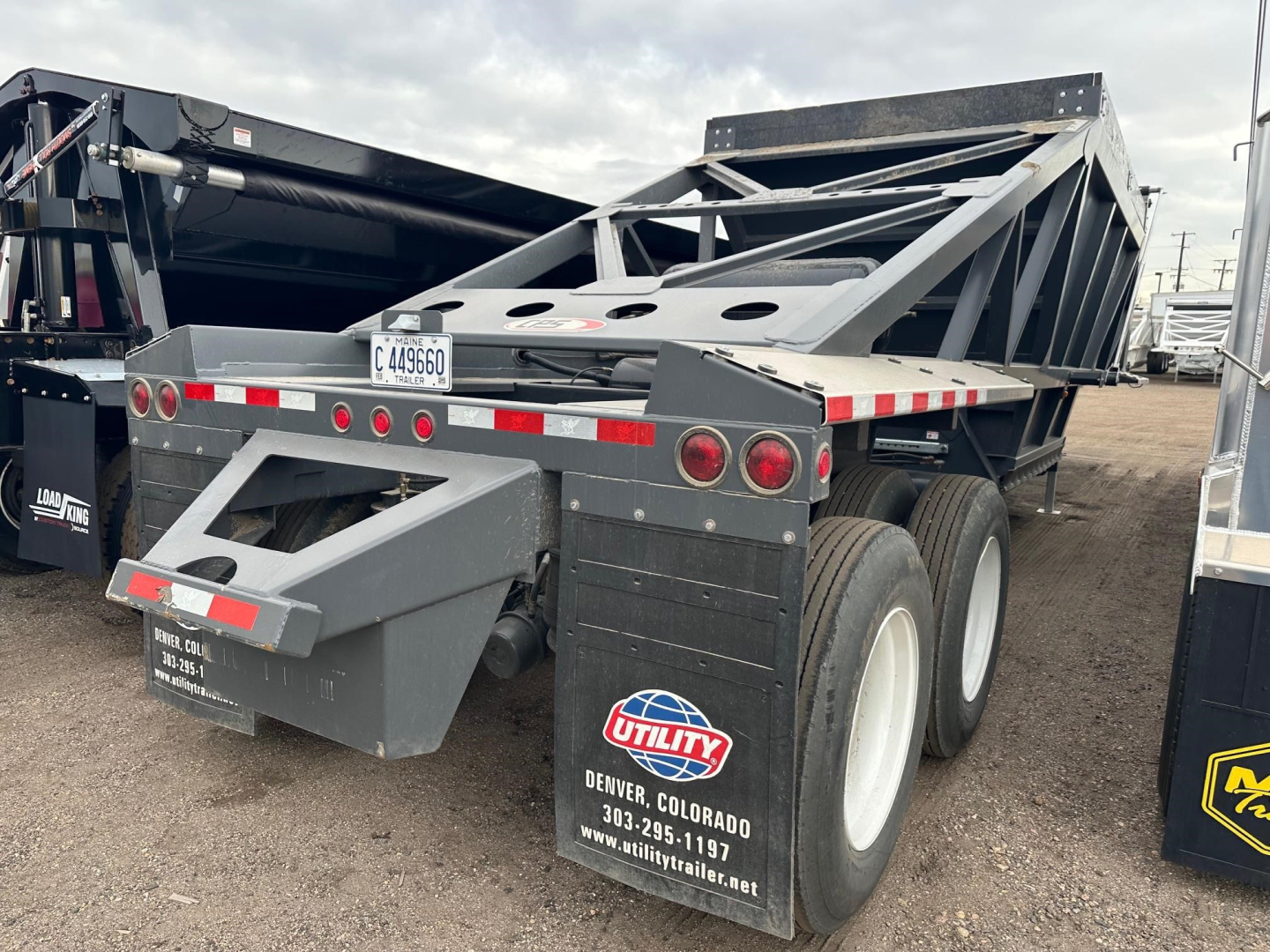 Bottom dump trailer rear and side view showing dual rear axles and Utility logo, with reflective tape and license plate area.