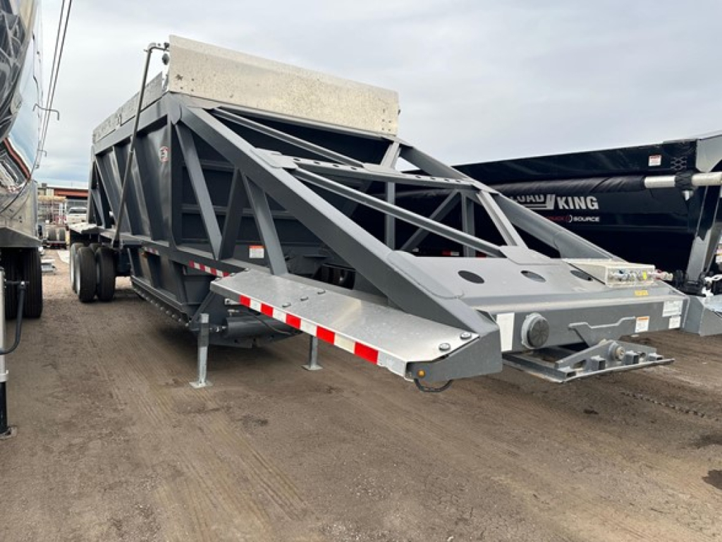 Trailer showing 40' light-weight air-ride bottom dump with gray frame, triangular truss sides, front hitch, and dual axles in an outdoor lot.