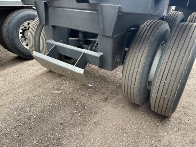 Trailer undercarriage with dual rear axles and landing gear, showing heavy steel frame and tires.