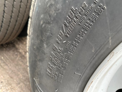 Suspension tire close-up showing markings on sidewall with tire size and load rating. 