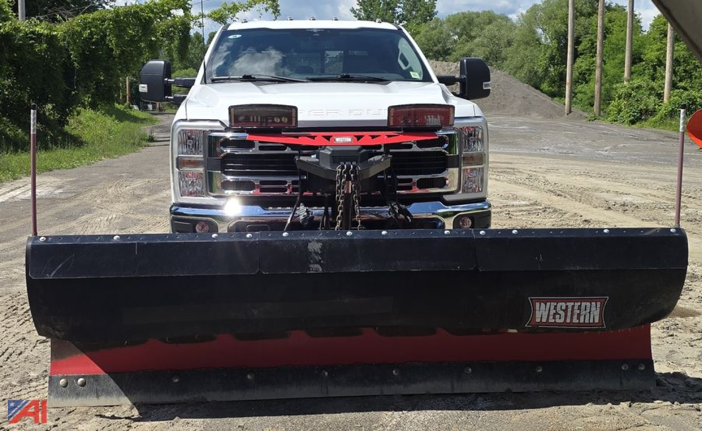 Front view of a white 2023 Ford F-350 Super Duty with a large plow attached, facing the camera in an outdoor lot.